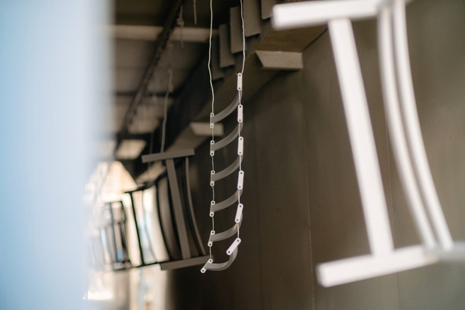 Small coated steel parts strung on wire hooks and hanging in a row.