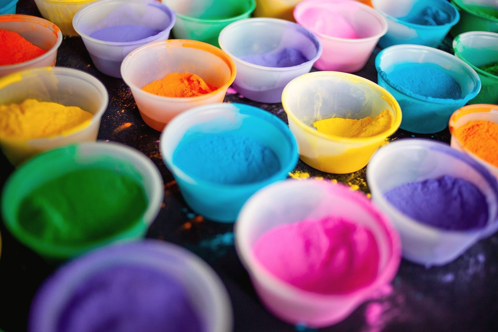 Rows of small bowls holding loose pigment powder in many colours.