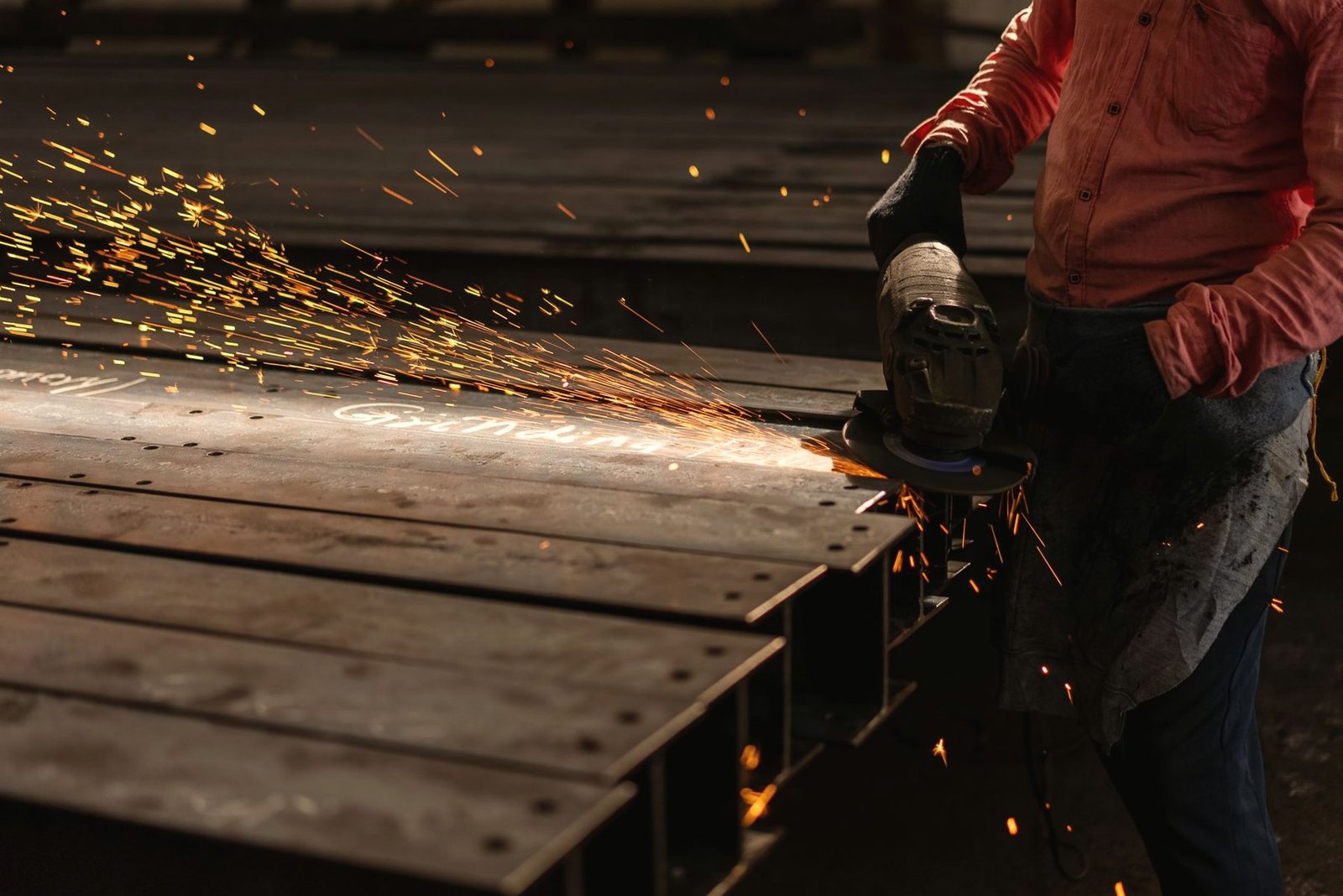 Sparks flying from an angle grinder running along a steel beam.