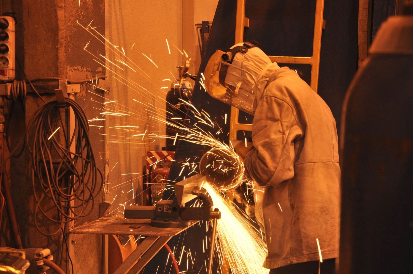 Sparks thrown across a workbench while a part is cut back.